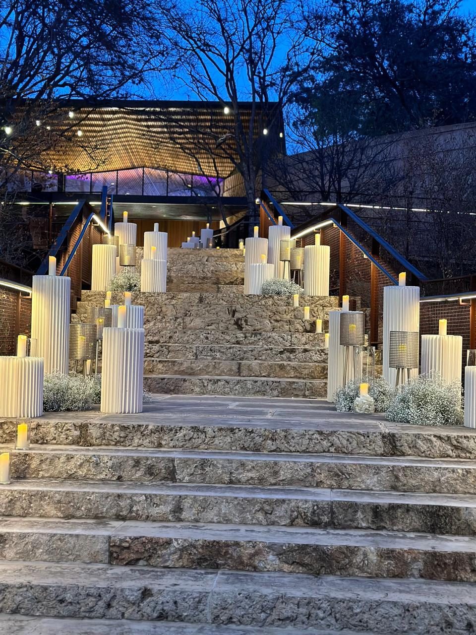 Stone stairway lined with fluted pillar candles and white florals at dusk