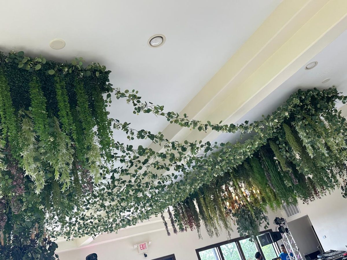 Sweeping ceiling installation of cascading eucalyptus and ivy across a pale ballroom ceiling