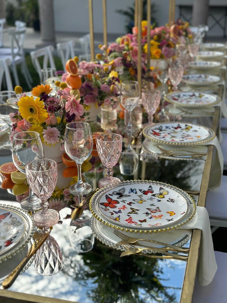 Close view of a place setting with a butterfly-patterned plate, cut glassware and spring florals