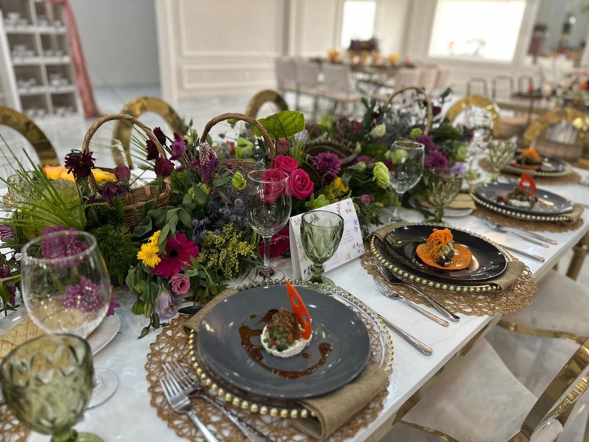 Close view of a place setting with gold charger, woven accents and a dense seasonal centerpiece