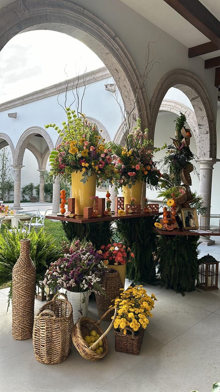 Arched hacienda corridor styled with tall floral urns, woven baskets and lanterns